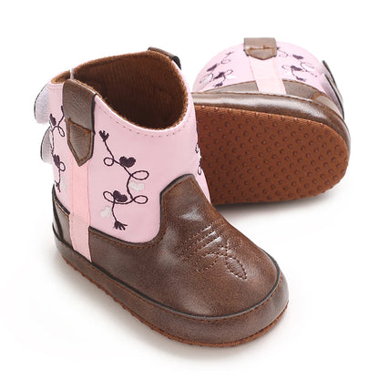 Angled view of a pair of pink baby girl western boots showing the soft non-slip sole construction.