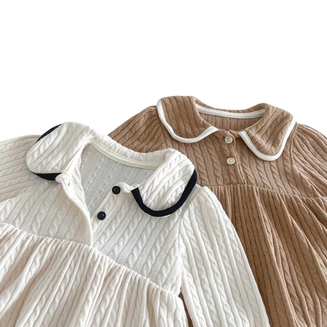 Close up view of the contrasting dark Peter Pan collar and dual front buttons on the ivory baby girl knit dress.