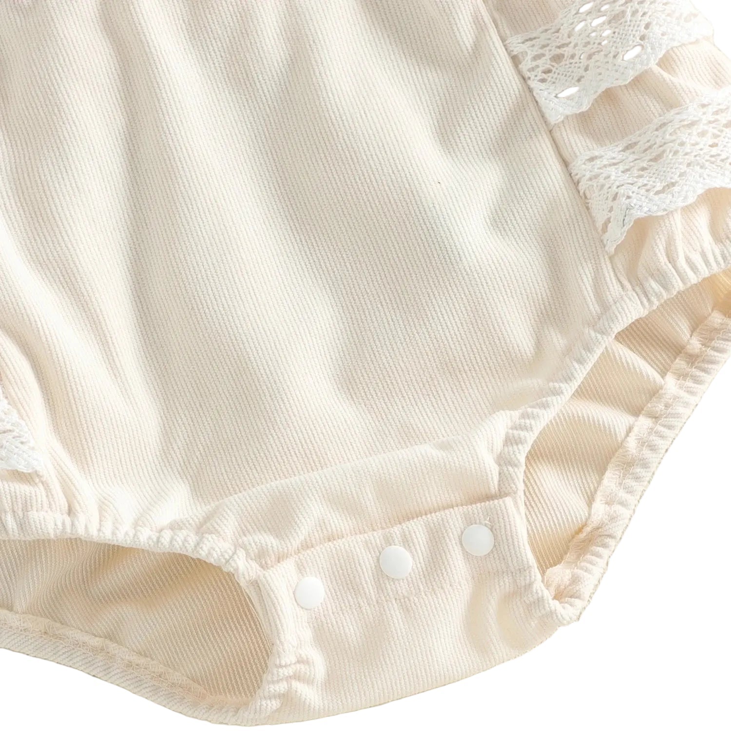 Close-up of the bottom of the ivory baby girl romper showing the convenient snap closures for diaper changes.