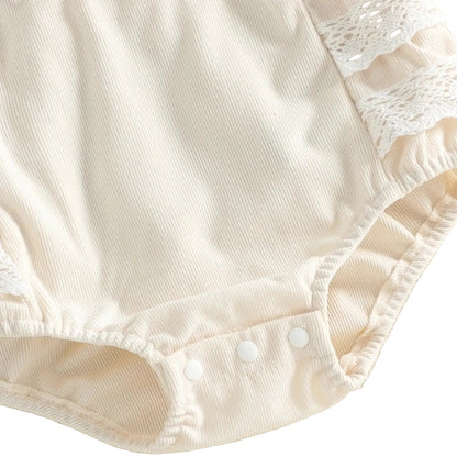 Close-up of the bottom of the ivory baby girl romper showing the convenient snap closures for diaper changes.