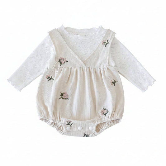 Front view of a 2-piece baby girl outfit featuring an ivory floral embroidered corduroy romper layered over a white long-sleeve top.