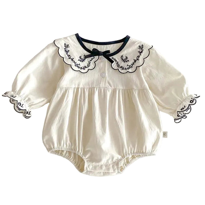 Front view of an ivory 100% cotton long sleeve baby girl bubble romper with floral embroidery on a scalloped collar and puff cuffs.