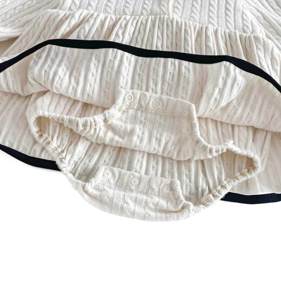 Close up of the bottom snap closure on the built-in bodysuit of the ivory baby girl romper dress.