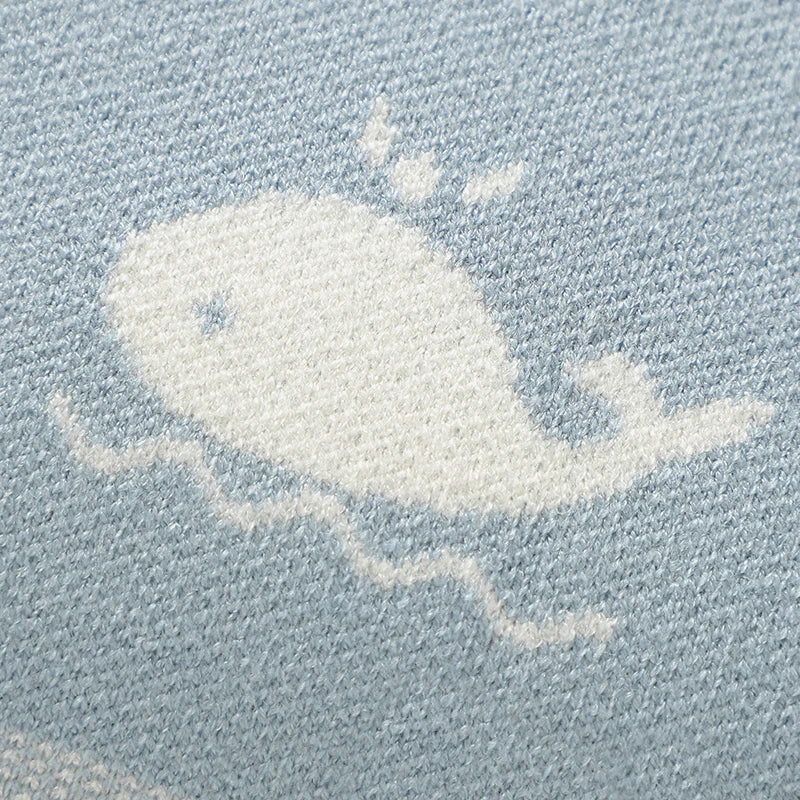 Close-up view of the white knitted whale pattern on soft baby blue viscose fabric