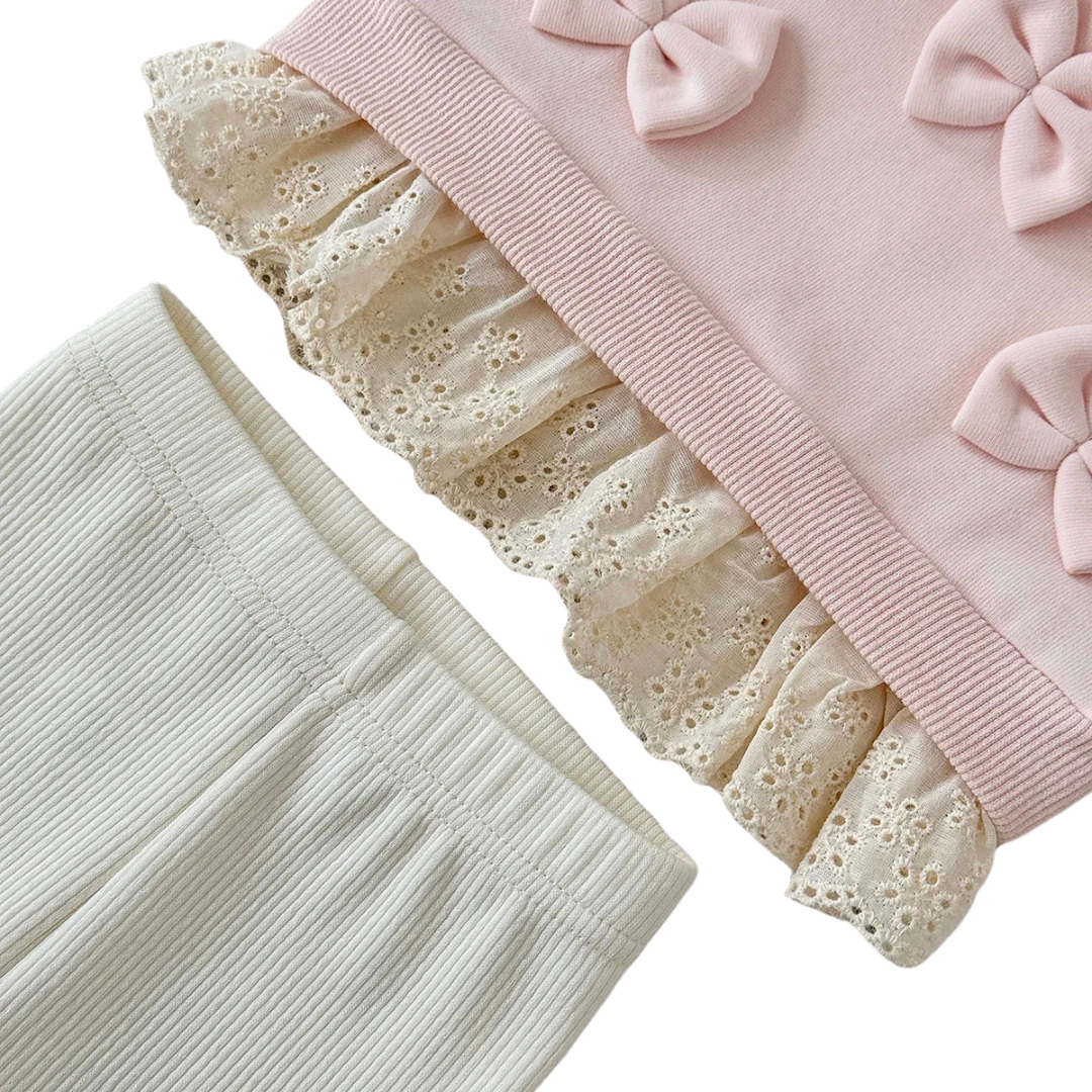 Close-up showing the delicate cream scalloped lace hem of the pink sweatshirt alongside the elastic waistband of the ribbed leggings.
