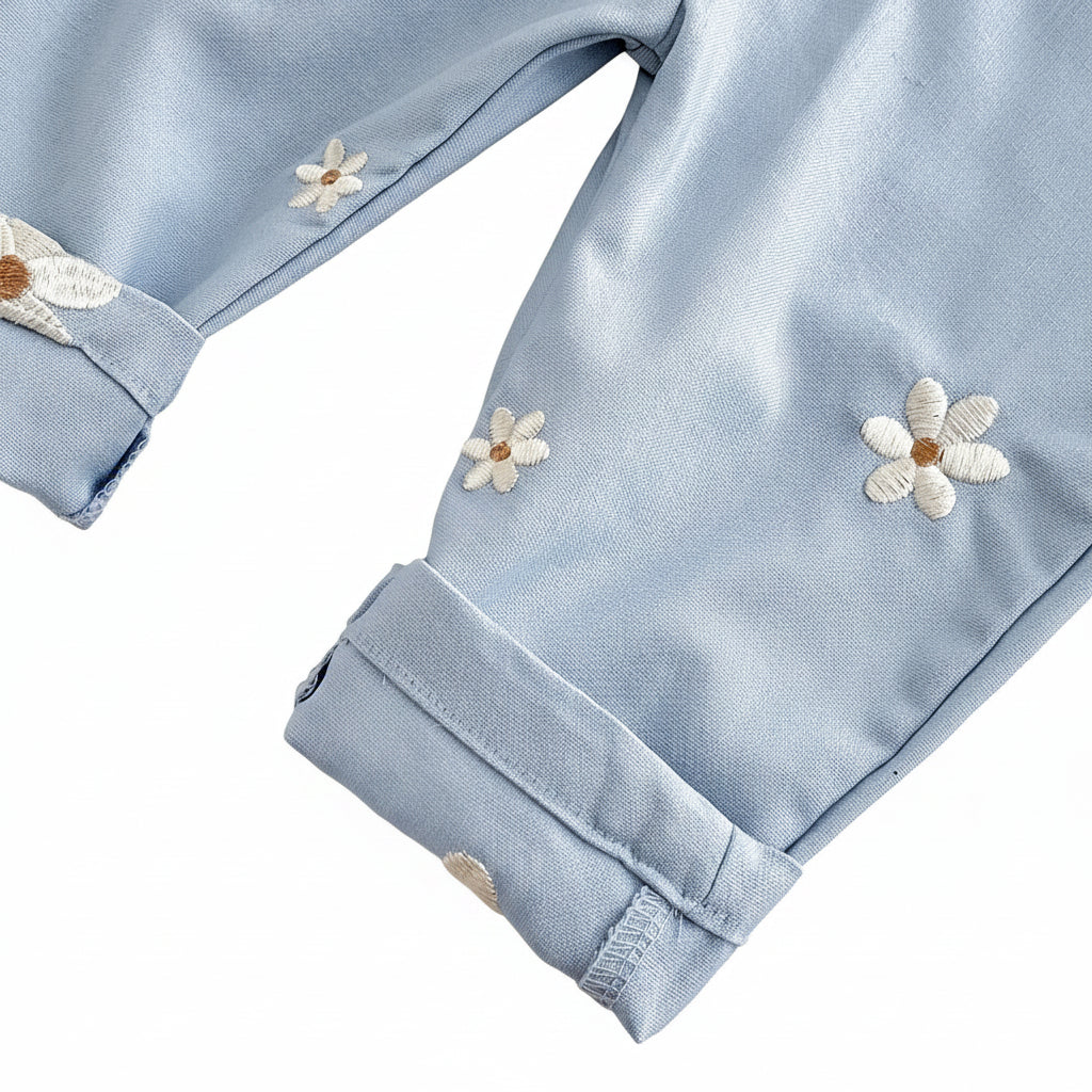 Close-up of the folded ankle cuff on light blue Kidsely overalls, highlighting the clean stitching and scattered white daisy embroidery.
