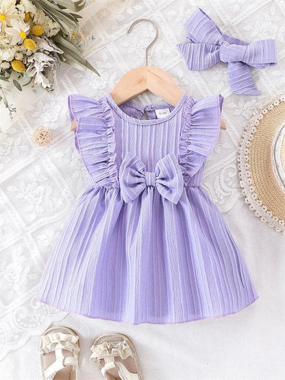 Front view of the light purple lilac baby girl summer outfit and headband set displayed on a wooden hanger.
