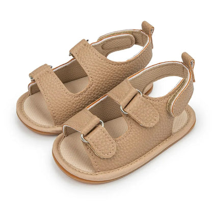Light tan or sand-colored vegan leather baby sandals with a soft interior and adjustable straps.