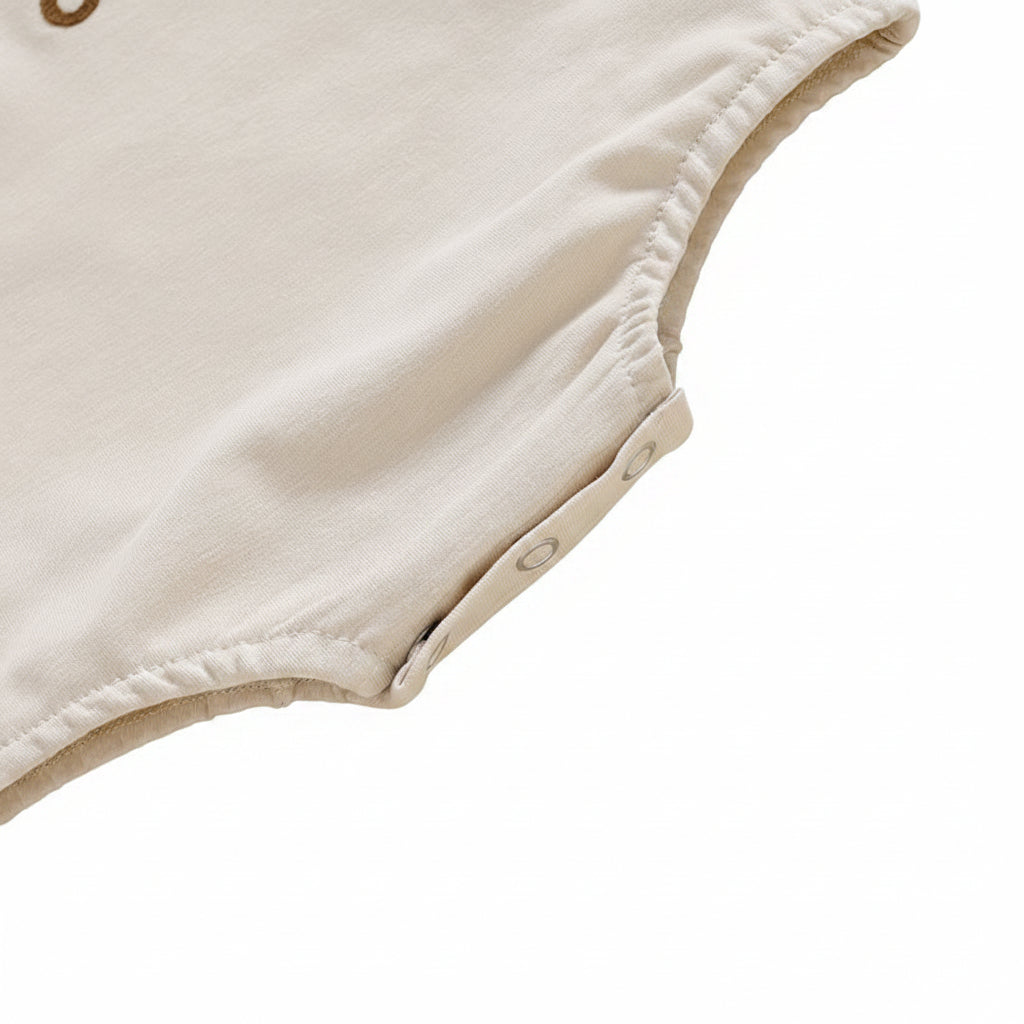 Close-up view of the secure premium snap button closure on the bottom of the baby girl romper for easy diaper changes.