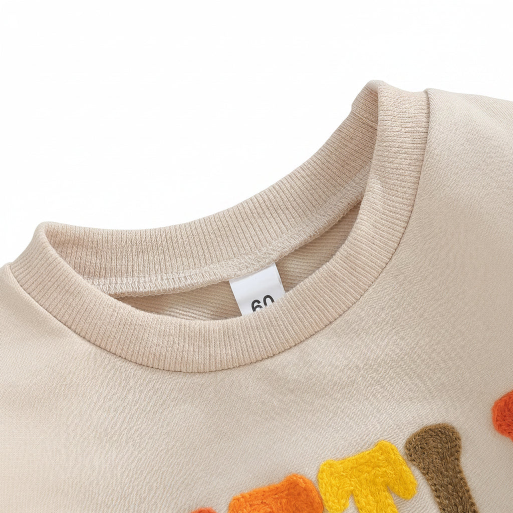 Close-up detail showing the ribbed crew neckline and the top of the colorful textured letter embroidery on the Little Bean cotton baby romper.