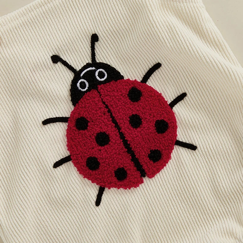 Detailed view of the premium red and black bouclé textured ladybug embroidery on ribbed corduroy fabric.