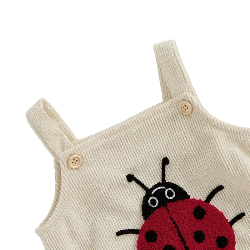 Close-up of the adjustable wooden-style shoulder buttons on the Little Lady ladybug romper.