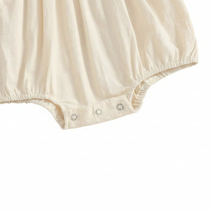 Close-up of the bottom diaper-changing area of the cream infant bodysuit highlighting the secure three-metal snap button closure system.