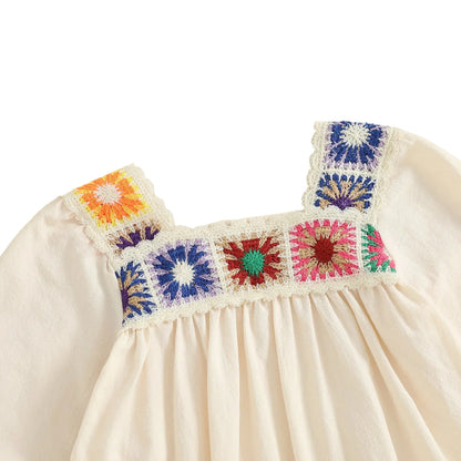 Detailed close-up view of the square collar and vibrant, multi-color embroidered crochet floral patchwork on the chest of the cream baby bodysuit.