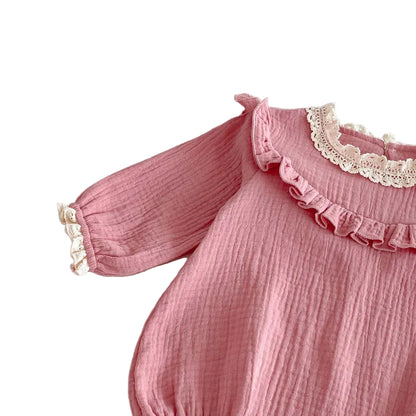 Close-up view of the right shoulder ruffle and long sleeve on a crinkle cotton dusty pink baby girl romper.