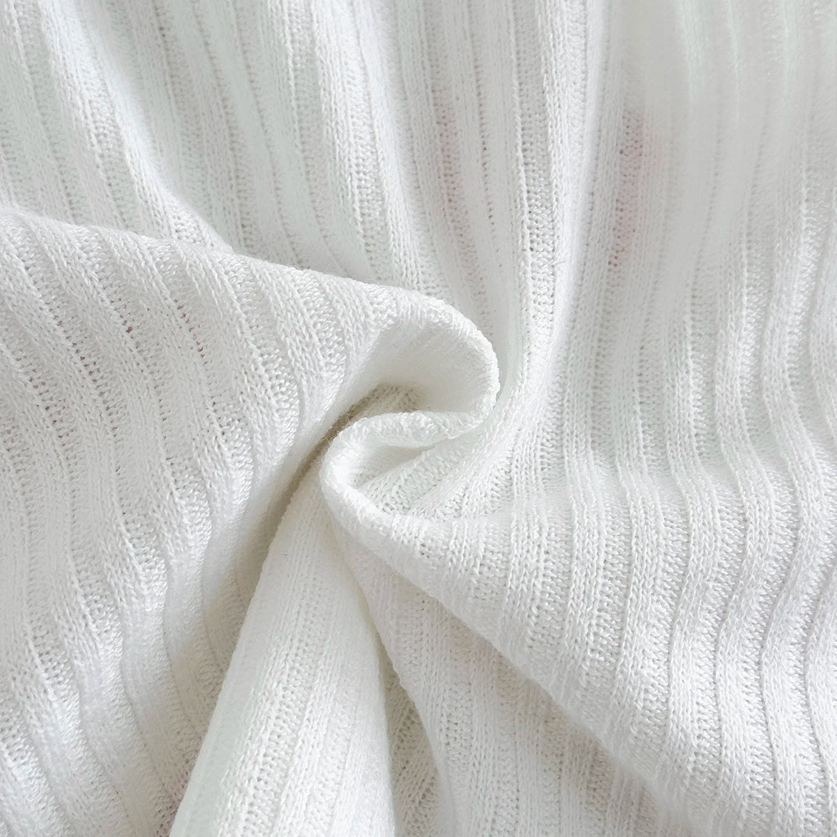 Macro view of the soft folds of the breathable marshmallow white ribbed knit polyester fabric blend used for the matching summer set.