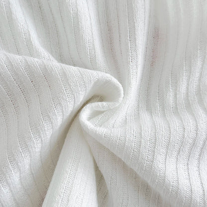 Macro view of the soft folds of the breathable marshmallow white ribbed knit polyester fabric blend used for the matching summer set.
