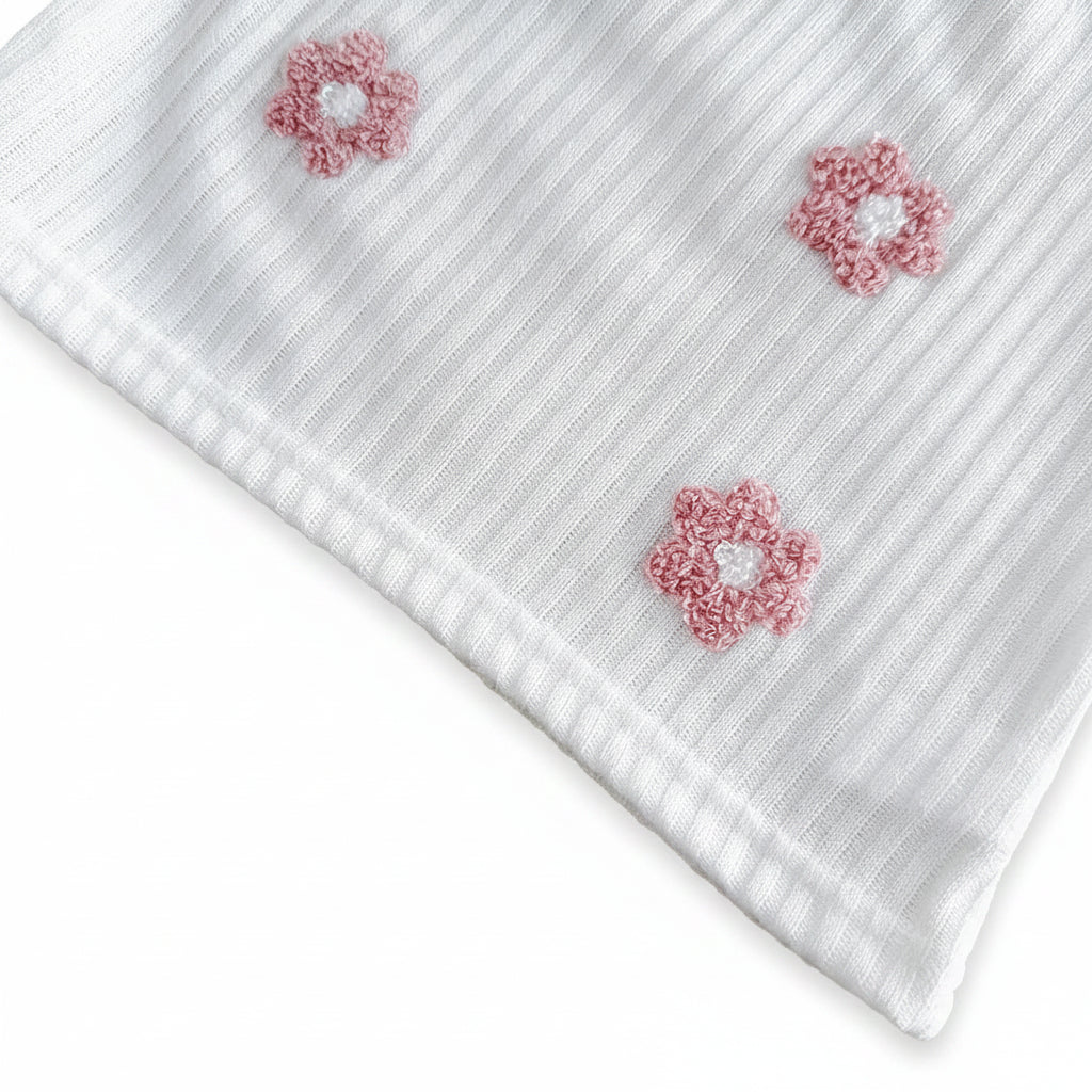 Detailed close-up of the pink 3D terry loop flower embroidery patches stitched onto the white ribbed knit fabric bodice.
