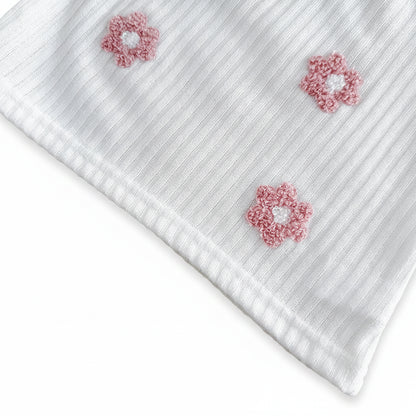 Detailed close-up of the pink 3D terry loop flower embroidery patches stitched onto the white ribbed knit fabric bodice.
