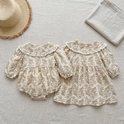 Matching baby girl floral bubble romper and toddler long sleeve dress displayed flat with a straw hat and blanket.