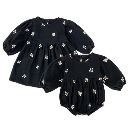 Sister matching set featuring a toddler girls black floral dress and coordinating baby girls black floral romper on a white background.