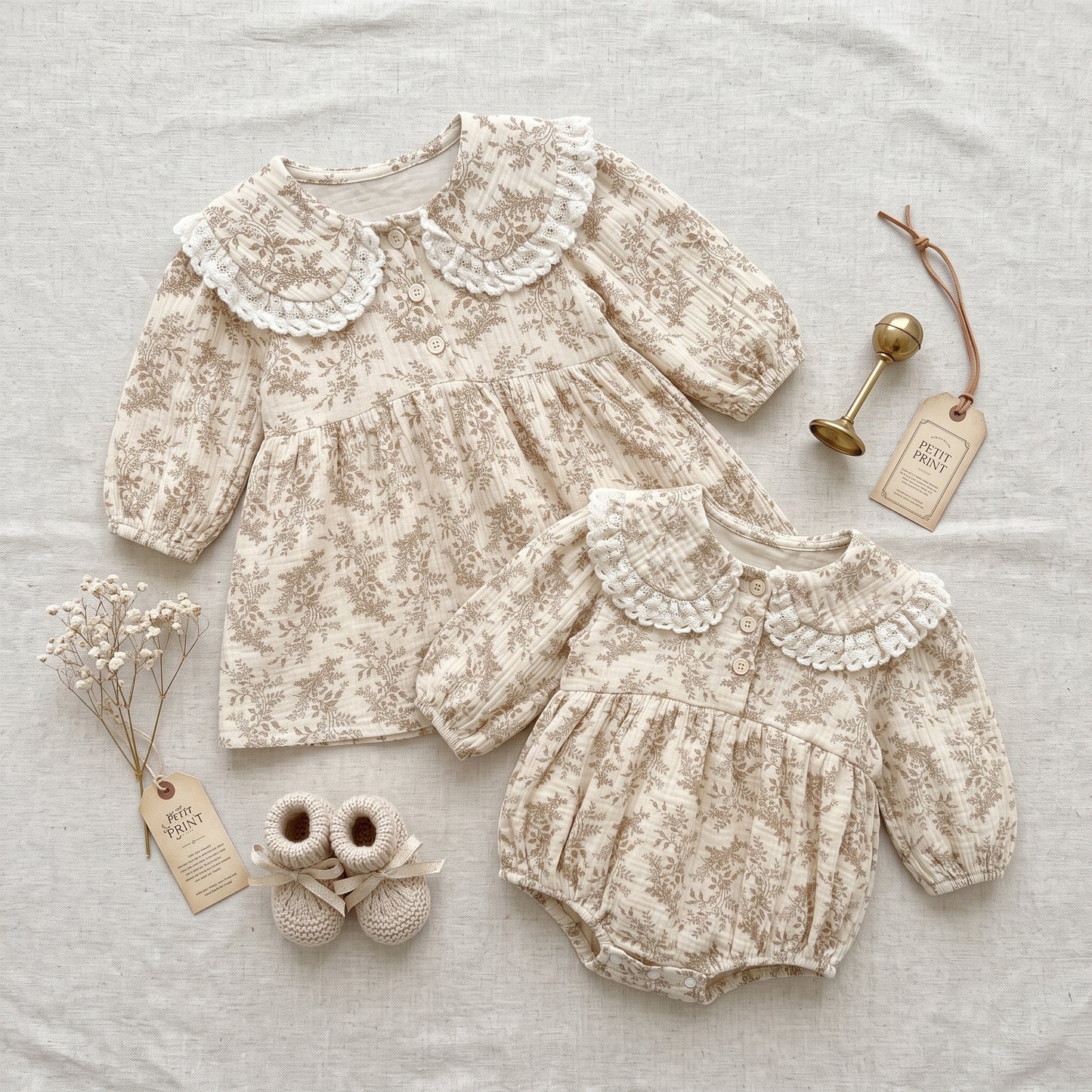 Flat lay of matching cottagecore floral baby romper and toddler dress set with vintage baby booties and accessories.