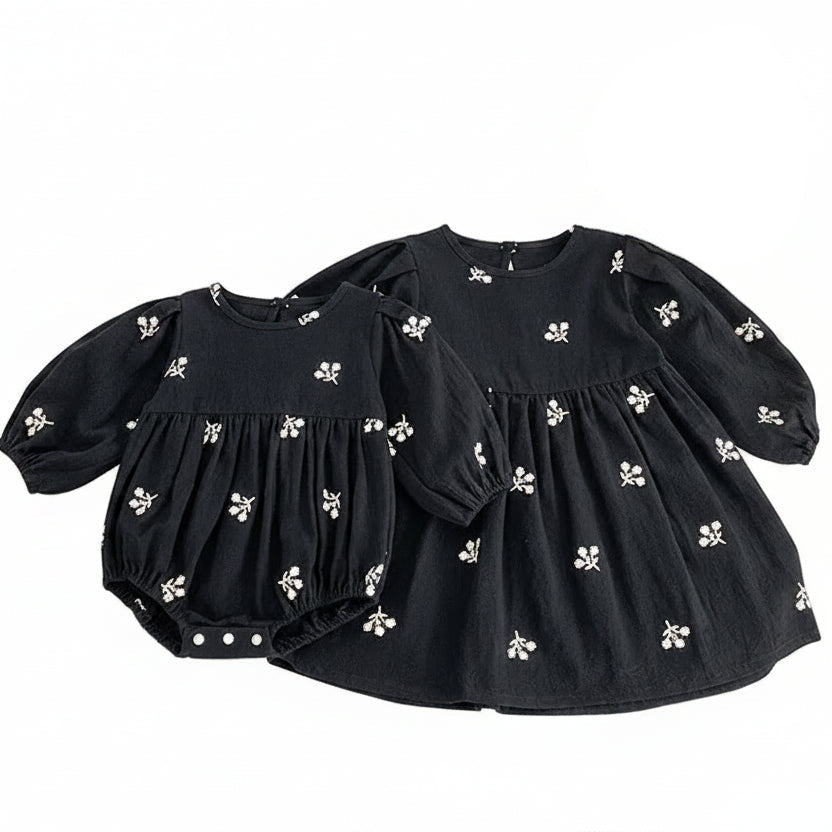 Sister matching set featuring a toddler girls black floral dress next to a coordinating baby girls black floral romper.