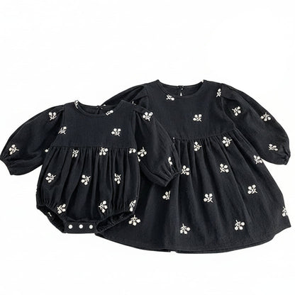 Sister matching set featuring a toddler girls black floral dress next to a coordinating baby girls black floral romper.