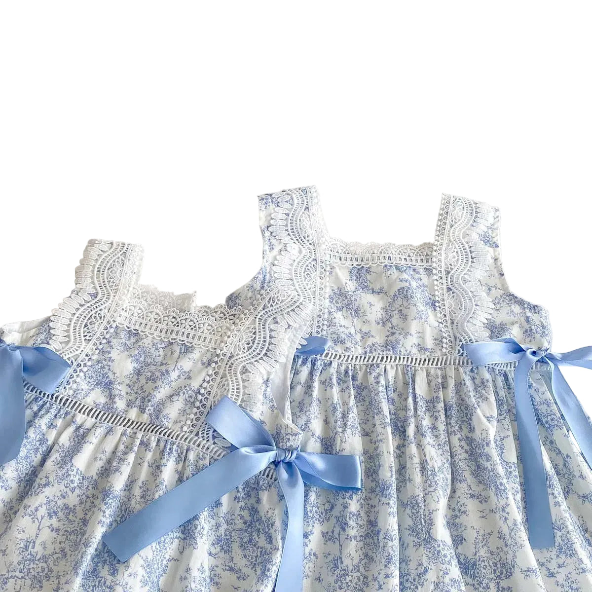 Front view of two blue toile floral dresses showing scale for toddler and little girl sizes.