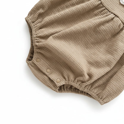 Close-up view of the gathered elastic leg opening on the mocha brown infant bubble romper.