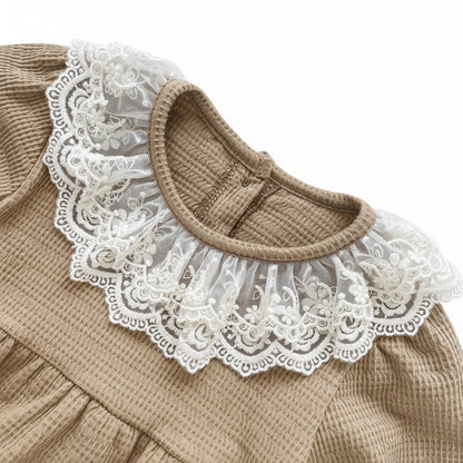 Front view detail of the elegant white lace collar on a mocha brown waffle knit baby bodysuit.