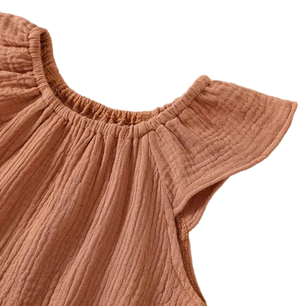 Detail shot of the flexible, soft elastic gathered neckline on the front of a rust terracotta cotton muslin baby bodysuit.