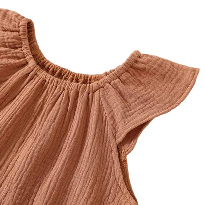 Detail shot of the flexible, soft elastic gathered neckline on the front of a rust terracotta cotton muslin baby bodysuit.