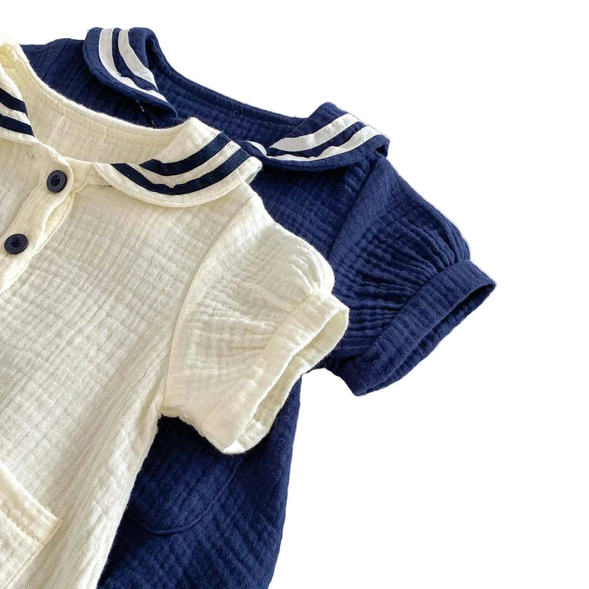 Angled view of both Sea Salt and Deep Sea muslin rompers showing the short sleeves and puff silhouette.
