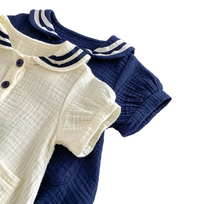 Angled view of both Sea Salt and Deep Sea muslin rompers showing the short sleeves and puff silhouette.