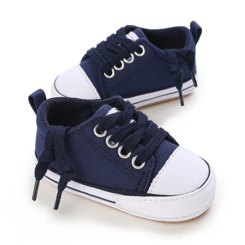 Navy blue infant athletic canvas sneaker with white laces and non-slip rubber sole.