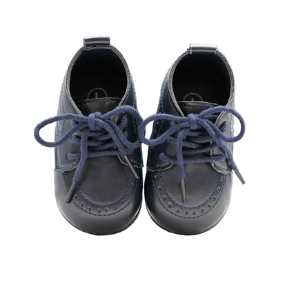 Front-facing view of a pair of Kidsely navy blue lace-up baby dress shoes showing the traditional brogue perforation detailing.