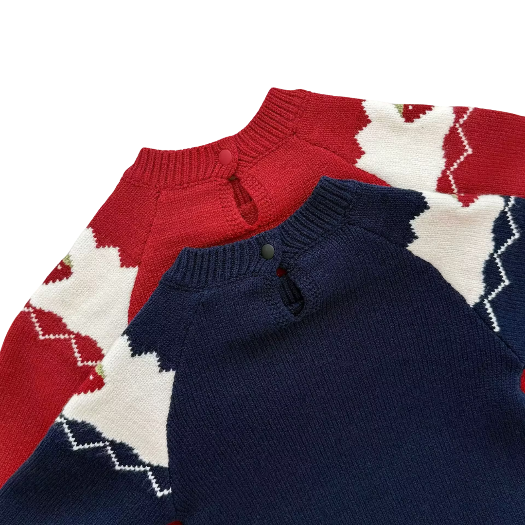 Detailed view of the knit strawberry pattern, back neckline button, and scalloped edge on the navy and red baby rompers.