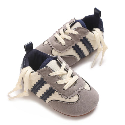 Neutral cream-colored baby sneakers with navy blue stripes, perfect for spring and autumn outfits.