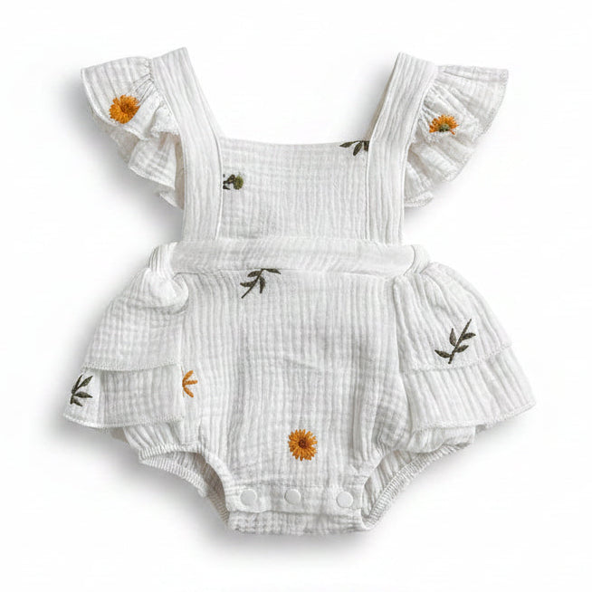Front view of a white cotton muslin baby girl romper featuring yellow sunflower and daisy embroidery, ruffle flutter sleeves, and snap closures on a white background.