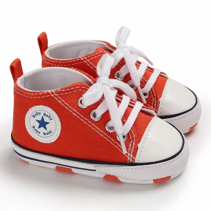 Bright orange infant canvas sneakers with non-slip traction dots for toddlers.