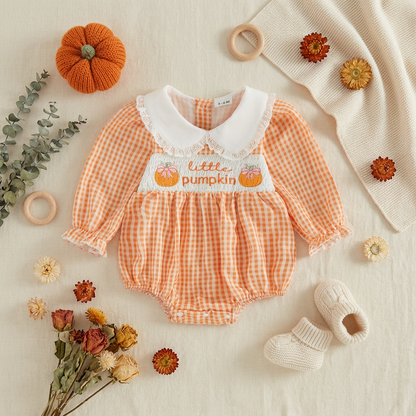 Fall themed flat lay displaying the baby girl orange gingham pumpkin romper surrounded by mini pumpkins, dried floral sprigs, a wooden teething ring, and white baby shoes.