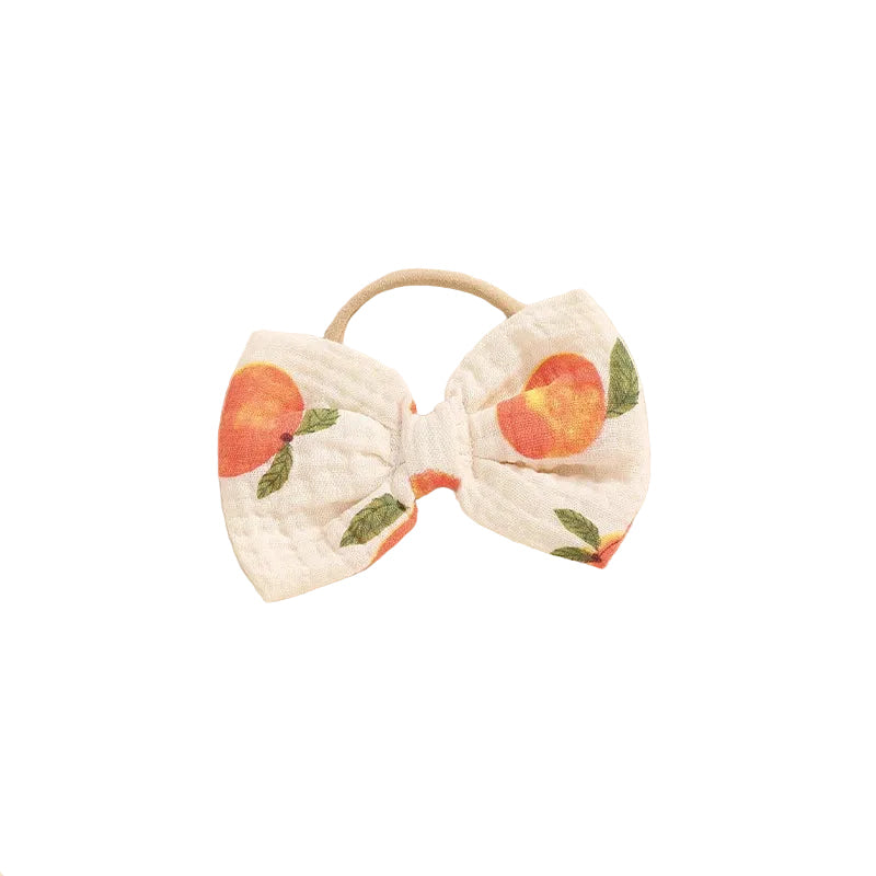 Close-up of the matching peach print baby stretch headband with a pre-tied bow.