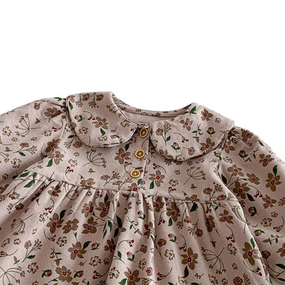 Close-up of the classic Peter Pan collar, gently gathered chest, and wooden-style front buttons on the floral toddler dress.