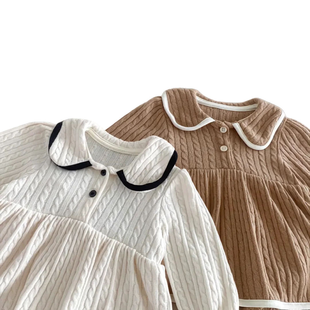 Close up of the classic Peter Pan collars and button details on the ivory and chestnut baby cable knit dresses.