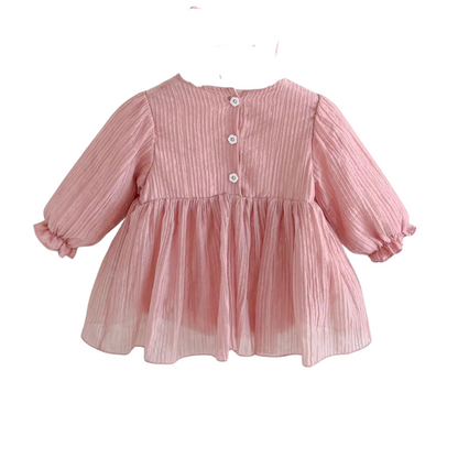 Back view of the dusty pink baby girl dress on a hanger showing the button closures at the back of the neck.