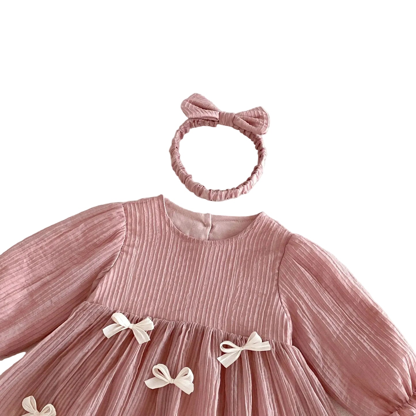 Close-up flat lay of the baby dress neckline, crinkle fabric texture, and the matching stretchy pink headband.