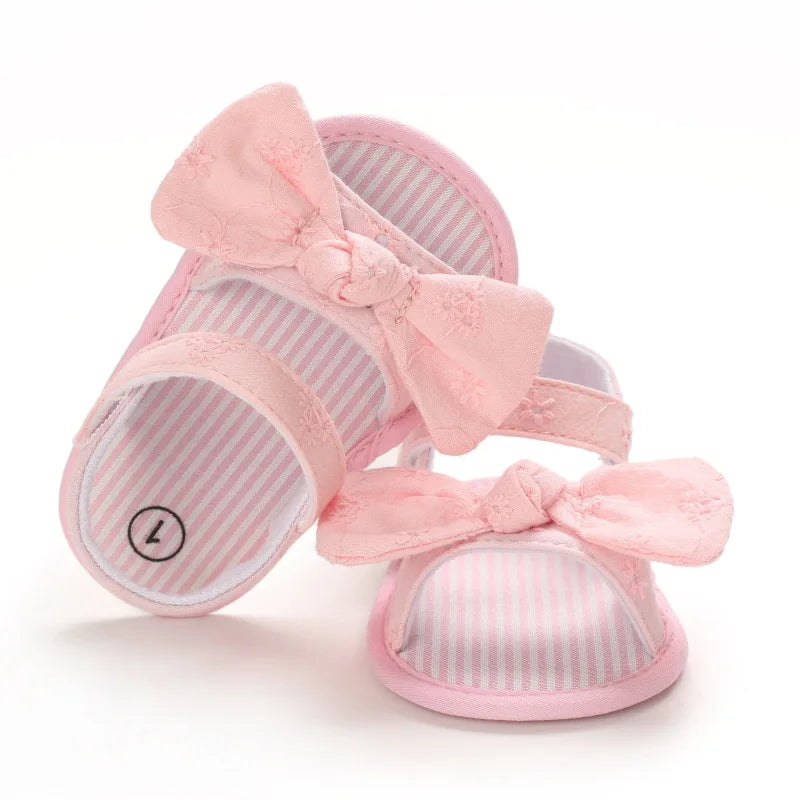 Front view of soft pink baby girl eyelet bow sandals showing the pink and white striped insole.