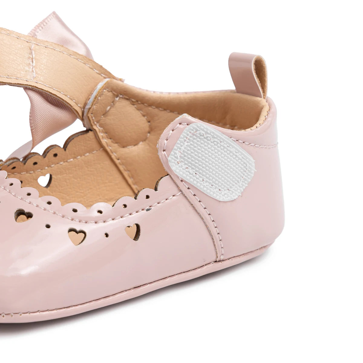 Side view of a pink baby girl Mary Jane shoe with the adjustable hook-and-loop strap pulled open to show ease of use.