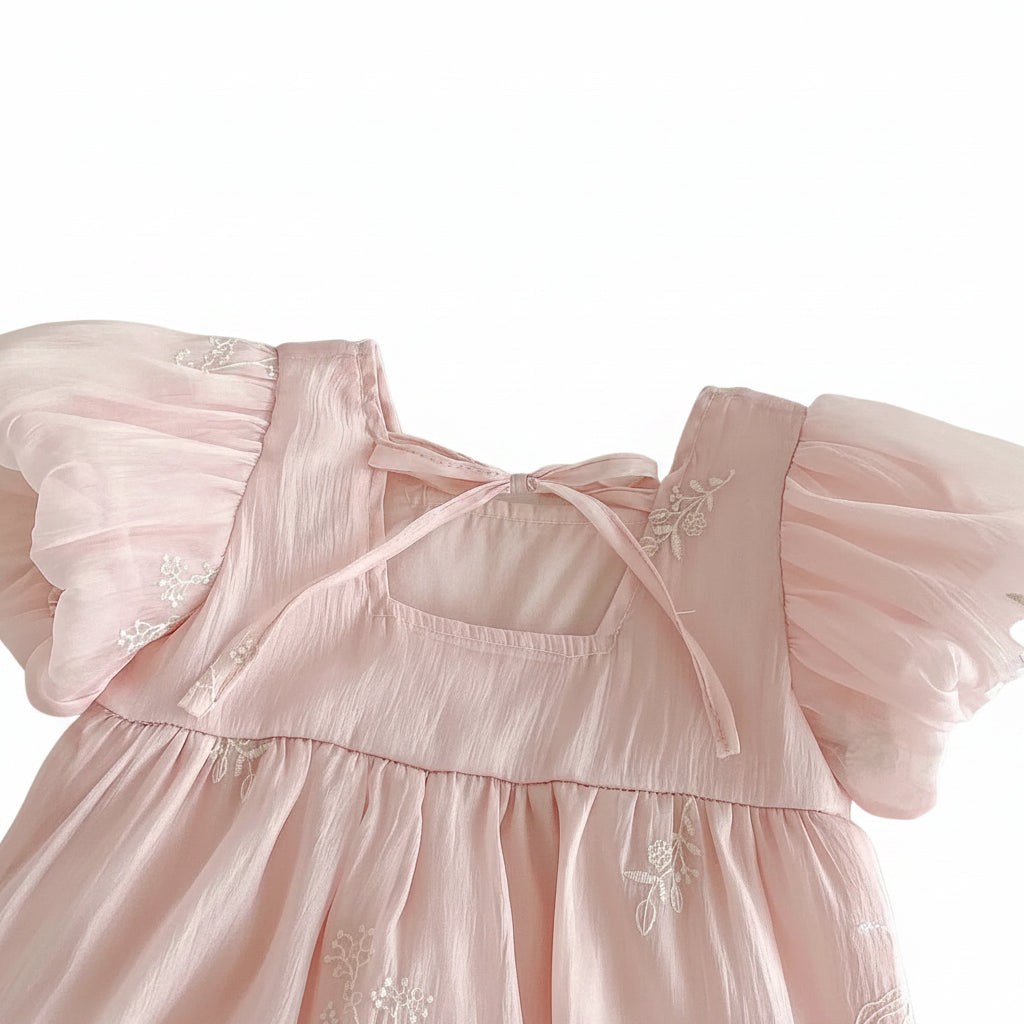 Close-up of the square neckline and adjustable fabric tie-back closure on the back of a pink baby girl romper.